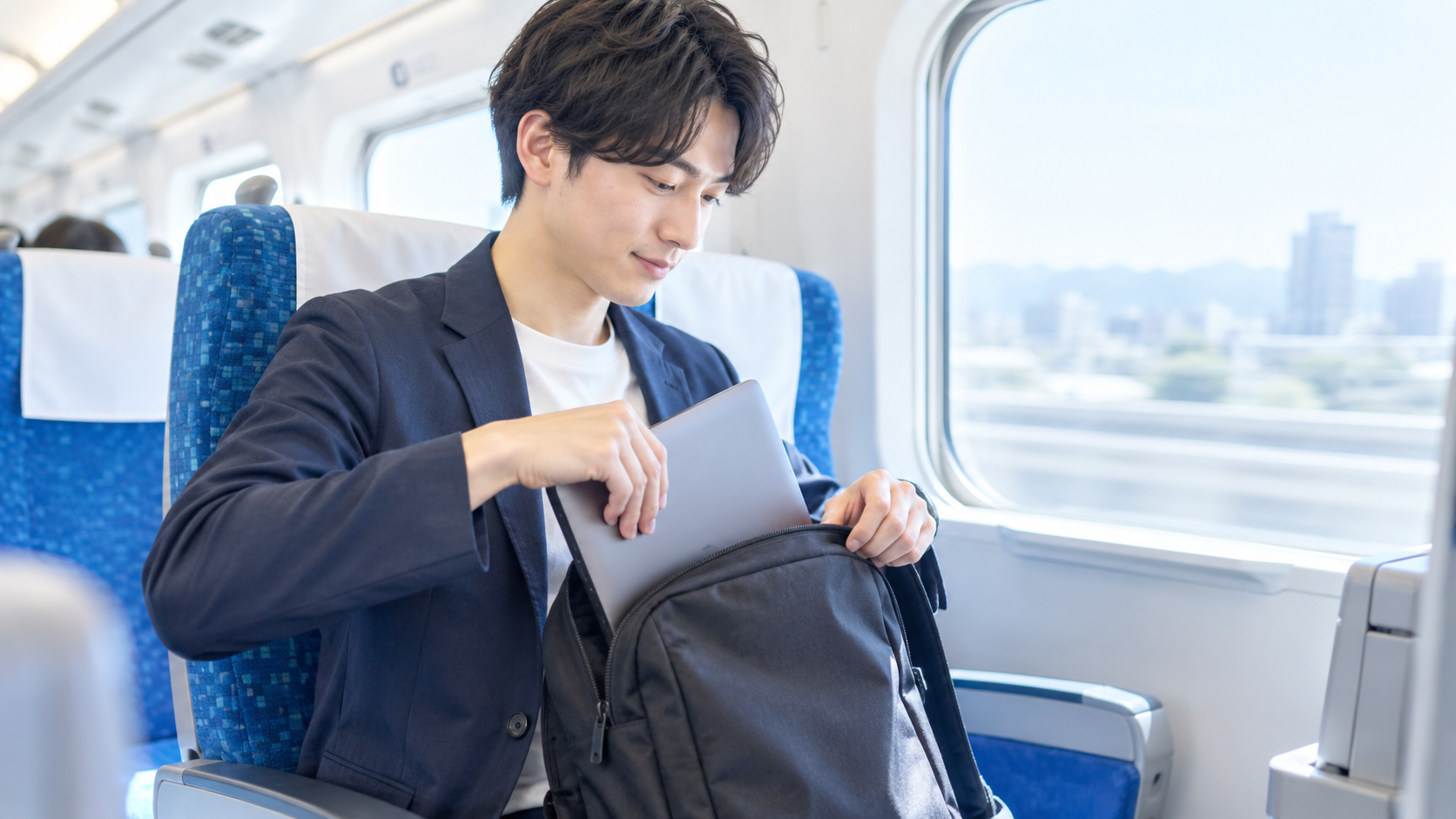 新幹線でノートパソコンを鞄から取り出すイメージ